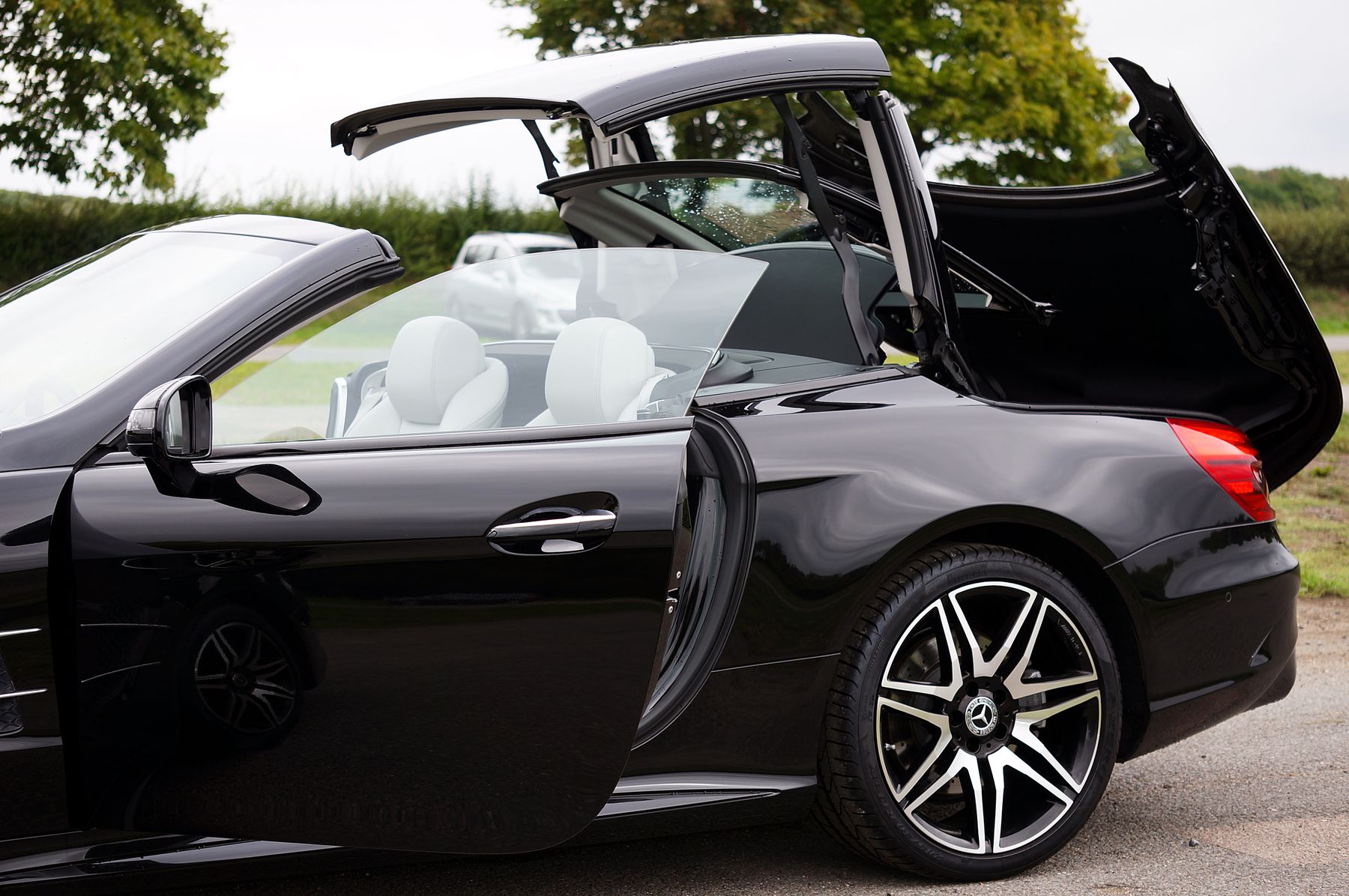 Black Mercedes-Benz SL with its retractable hardtop folding into the trunk